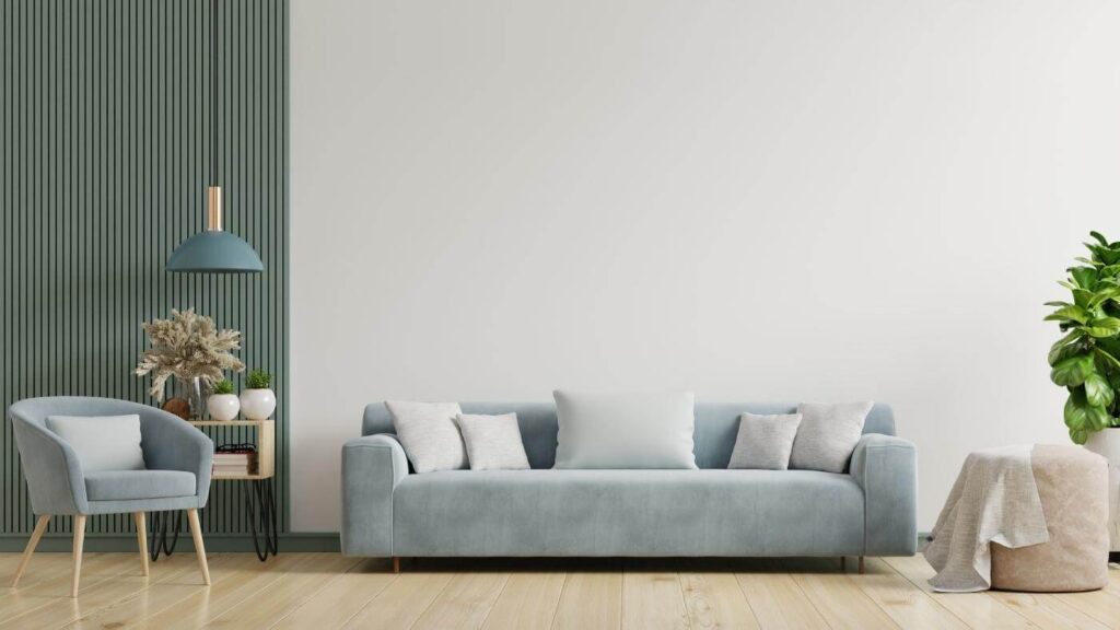 Sala de estar composta por um sofá 3 lugares cinza em camurça, uma poltrona do mesmo material e um puff bege.